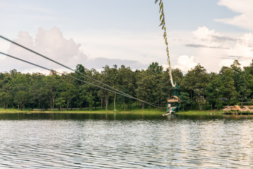 Young woman crossing a lake in zip line