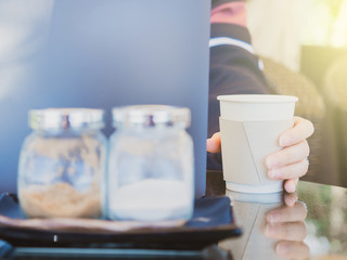 business with outdoor travel concept from beauty woman hand use laptop and put paper cup of coffee at counter of coffee bar