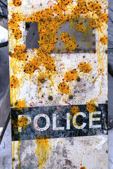 Shield of a policeman bombarded with paintball cartridges with paint