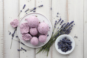 Natural cosmetics. Handmade lavender bath bombs and lavender flowers on white wooden planks, top...