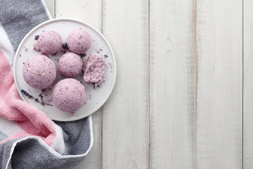 Handmade lavender bath bombs with towel on white wooden planks, top view
