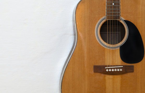 Acoustic guitar on a textured white wall
