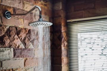 Shower in bathroom flowing water drop to the floor at modern home of brick style near window