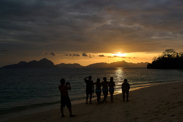 Fototapeta premium Silhouette of a couple walking on the beach at sunset in El Nido, Palawan, Philippines