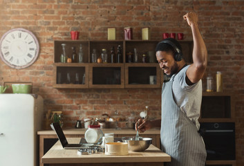 African american man listening to music and dancing in kitchen