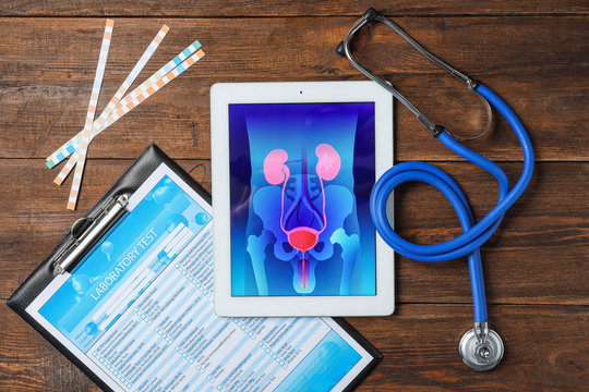 Flat lay composition with tablet, stethoscope and test form on wooden background. Urology concept