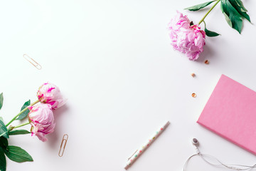 Feminine workspace with pink peons on white background with copy space