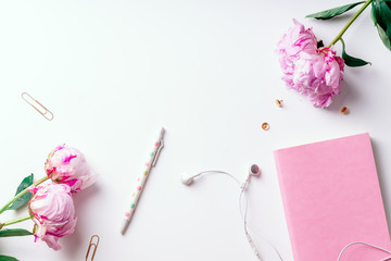 Feminine workspace with pink peons on white background with copy space
