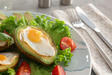 Eggs baked in avocado and fresh vegetables on plate, closeup