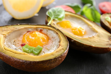 Avocado baked with eggs on table, closeup