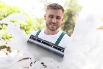 Male cleaner wiping window glass with squeegee from outside