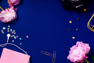 Flat lay composition with peons, earphones, sparkles and vintage photo camera on blue background. Top view, colorful workspace concept