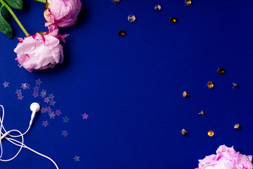 Flat lay composition with peons, sparkles and accessories on blue background. Top view, colorful workspace concept