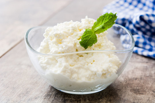 Fresh cottage cheese in a crystal bowl on wooden table. Copyspace