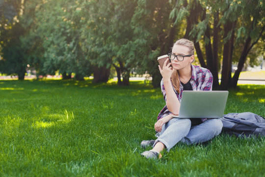 Serious young woman using laptop in park