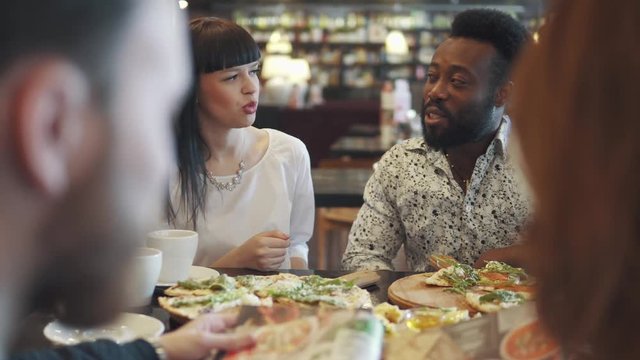 multi-ethnic group of friends in a cafe. young black man and girl have fun talking and eating