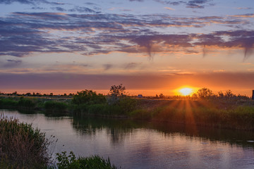 Silence, sunset in the steppe, beautiful clouds and the water surface of the canal.