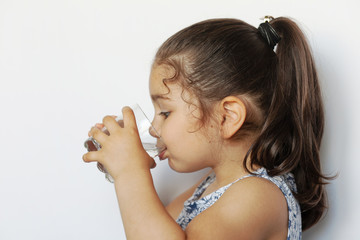 Cute little girl holding glass of water. and Child drinking water.