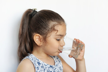 Cute little girl holding glass of water. and Child drinking water.