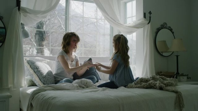 Slow motion of mother and daughter playing hand clapping game in bed / Pleasant Grove, Utah, United States