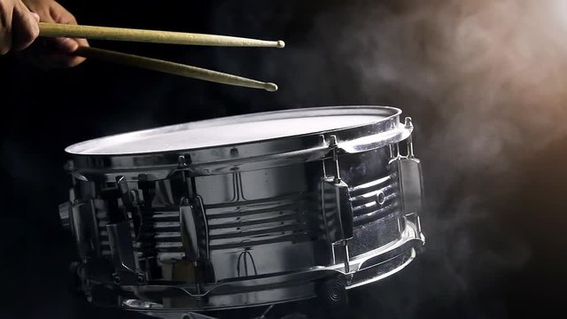 Dust from snare drum with hand and drum sticks in black background, close-up, low key, video, footage
