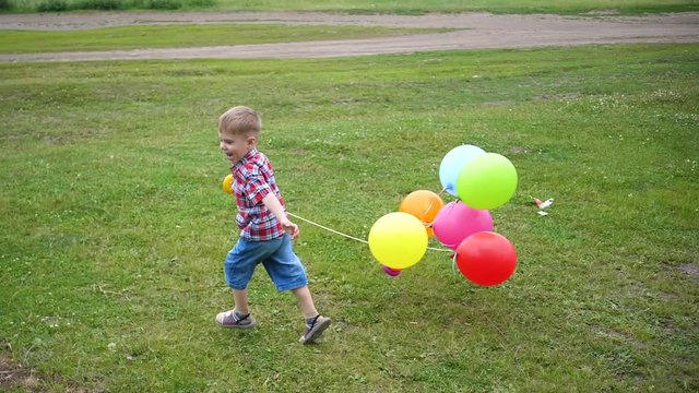 Happy little baby, fun running around with balloons. Outdoor recreation. Celebration and fun.Child's birthday