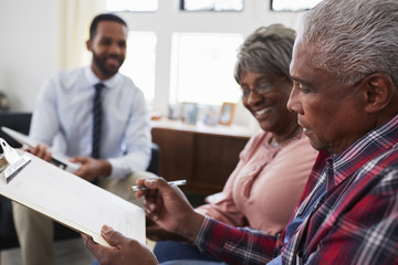 Obraz premium Senior Couple Meeting With Male Financial Advisor At Home And Signing Document