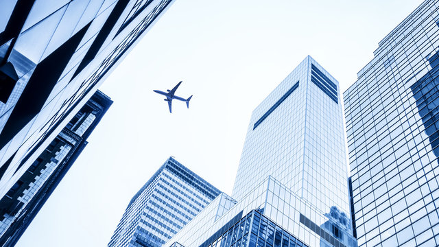 Fototapeta a plane flying over modern buildings of New York City