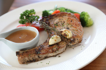 grilled pork chop with vegetable on dish with wood table background