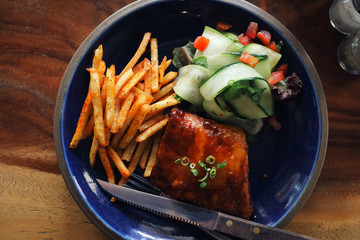 barbecued pork ribs steak with fresh vegetables on an old rustic wooden in restaurant