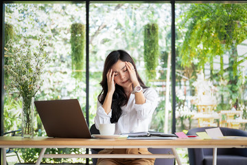 young business woman sitting at table in office feeling tired and stressed, business concept