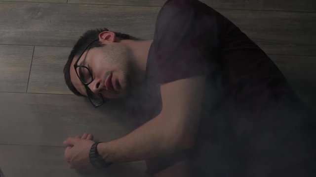 passed out man on the floor during a fire emergency coughing because of the smoke he is breathing. Toxic fumes floating in the air around him. 