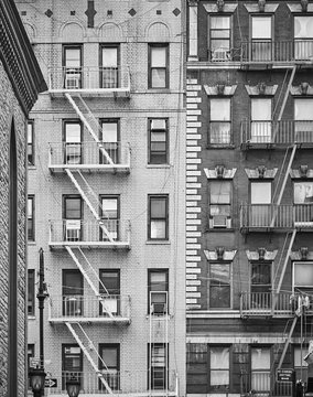 Black and white picture of residential buildings with fire escapes in New York City  USA.