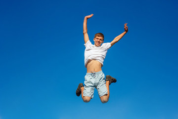 Fototapeta na wymiar happy boy jumping in the blue sky , concept of happiness