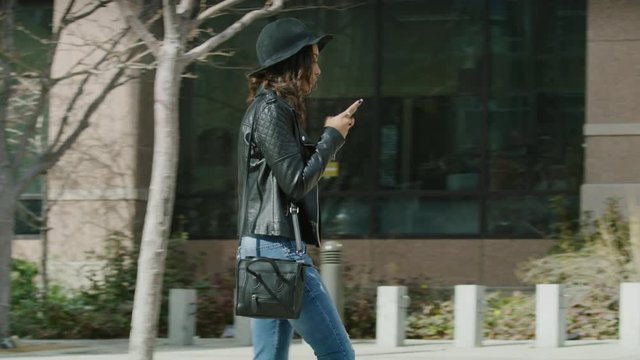 Slow motion shot of distracted woman texting on cell phone walking into post on sidewalk / Salt Lake City, Utah, United States