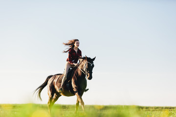 Young girl dressed casually riding a horse.