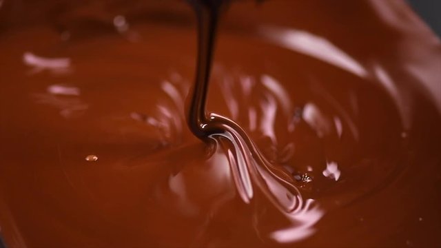 Chocolate. Pouring melted liquid premium dark chocolate closeup. Confectionery. Slow motion 4K UHD video 3840X2160
