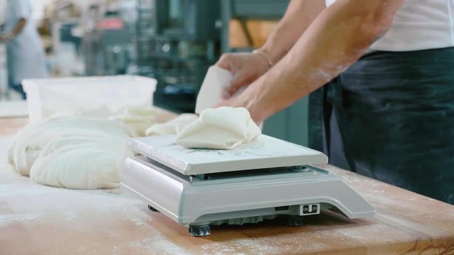 Professional baker divides the dough into portions and weights them