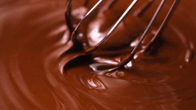 Chocolate. Mixing melted dark chocolate with a whisk. Closeup of liquid hot chocolate swirl. Confectionery. Slow motion 4K UHD video 3840X2160