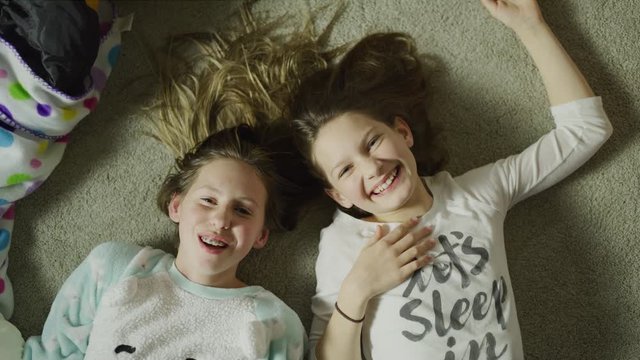 High angle view of portrait of laughing girls at sleep over laying on floor / Cedar Hills, Utah, United States