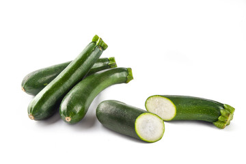 Three courgettes on a white background and one cut in half