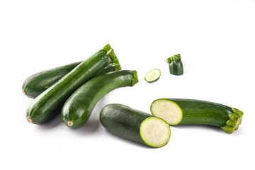 Three courgettes on a white background and one cut in half