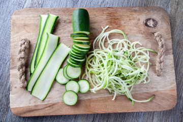 Top view of Courgette prepared on a wooden chopping board. Sliced, julienne and spaghetti