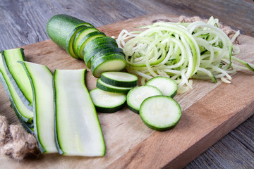 Courgette prepared on a wooden chopping board. Sliced, julienne and spaghetti