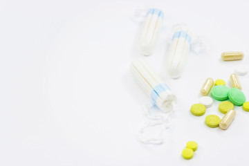 Tampons and pills on a white background