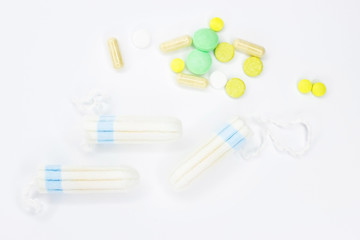 Tampons and pills on a white background