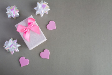 Gift  with pink bow and hearts  on the grey background.Top view.Copy space.