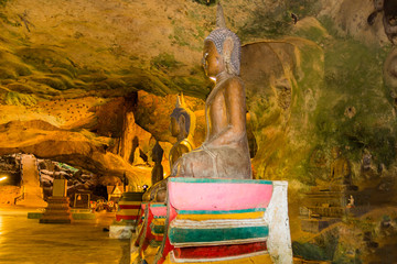golden buddha statues along the wall inside the cave