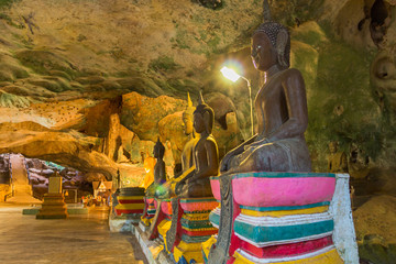 golden buddha statues along the wall inside the cave