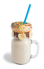 Banana milkshake in a glass jar (mason jar) with donut, isolated on white background.